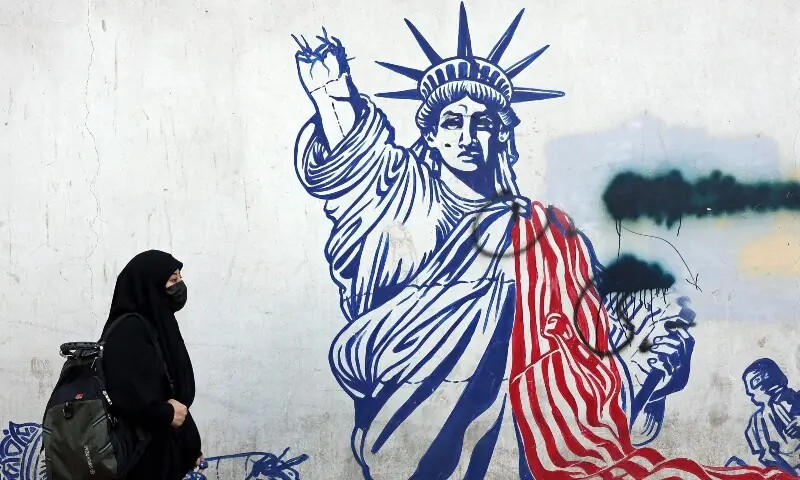 An Iranian woman walks past an anti-US mural next to the former US embassy in Tehran on February 26. &mdash; AFP
