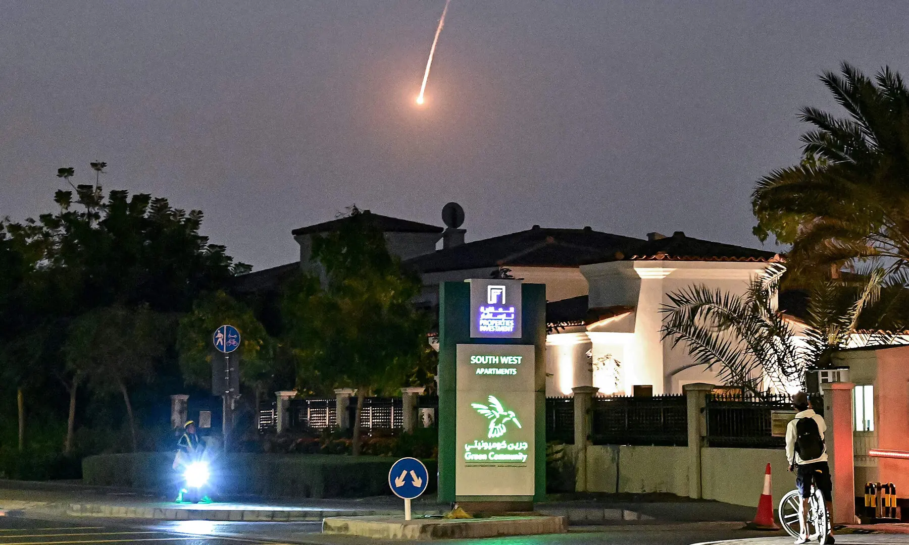  A cyclist watches as a projectile falls over Dubai on February 28, 2026. &mdash; AFP 