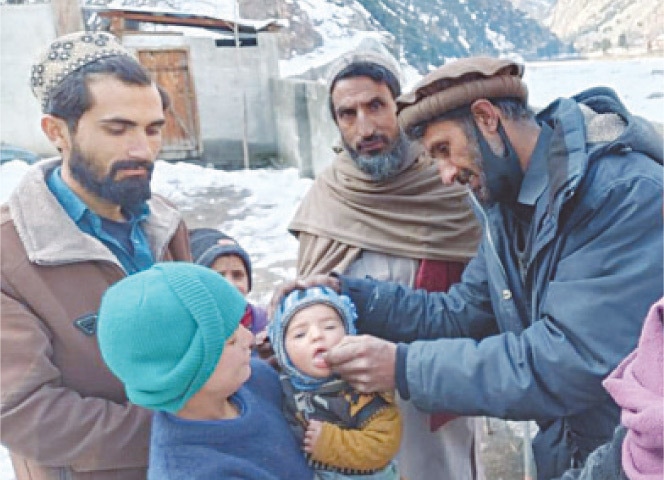 A health worker administers polio drops to a child in a snowbound area of Upper Kohistan on Tuesday. — Dawn