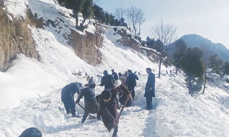 Young volunteers remove snow from the road in order to enable stranded Tirah families to evacuate to Bara. &mdash; Dawn