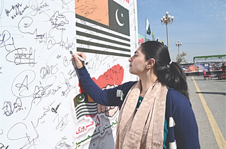 A participant signs a resolution displayed on a board showing solidarity with Kashmiris during a rally held from China-chowk to D-chowk in Islamabad on Thursday. &mdash; APP