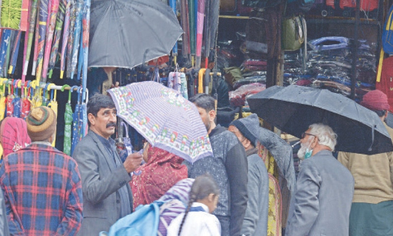 People purchase umbrella from a shop in Raja Bazaar in Rawalpindi on Tuesday. — Photo by Mohammad Asim People purchase umbrella from a shop in Raja Bazaar in Rawalpindi on Tuesday. — Photo by Mohammad Asim