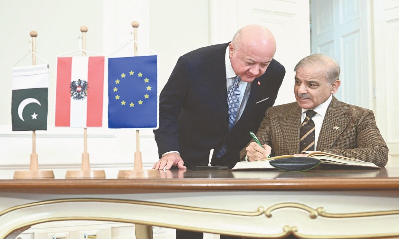 Austrian Chancellor Christian Stocker leans over as Prime Minister Shehbaz Sharif signs the guest book during an official visit to Vienna.&mdash;AFP