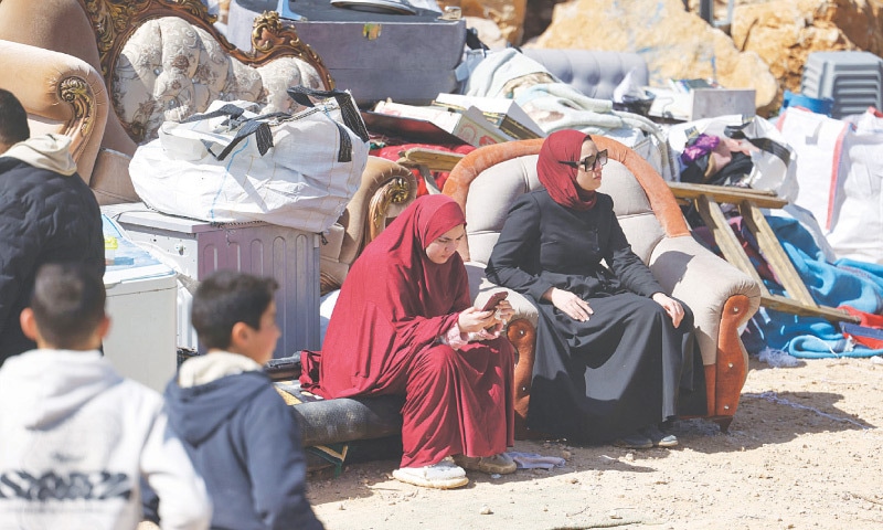 MEMBERS of a Palestinian family sit next to their belongings after their building was demolished by Israeli bulldozers near the settlement of Hagai, south of the occupied West Bank city of Hebron.—AFP MEMBERS of a Palestinian family sit next to their belongings after their building was demolished by Israeli bulldozers near the settlement of Hagai, south of the occupied West Bank city of Hebron.—AFP