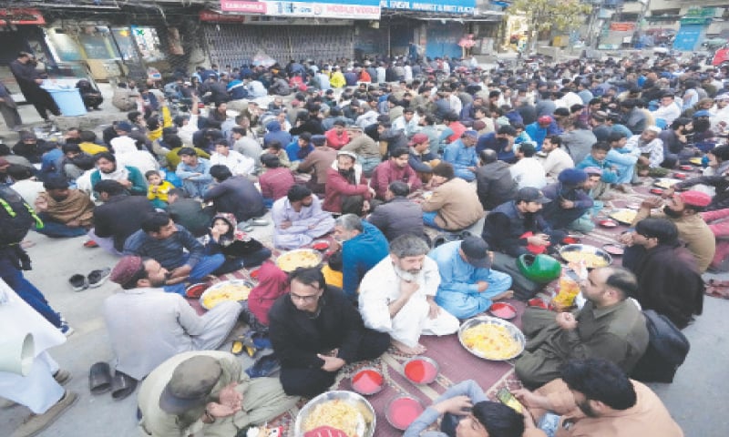 People wait for Iftar arranged by traders along Liaqat Road in Rawalpindi on the first day of Ramazan on Thursday. &mdash; Photo by Mohammad Asim
