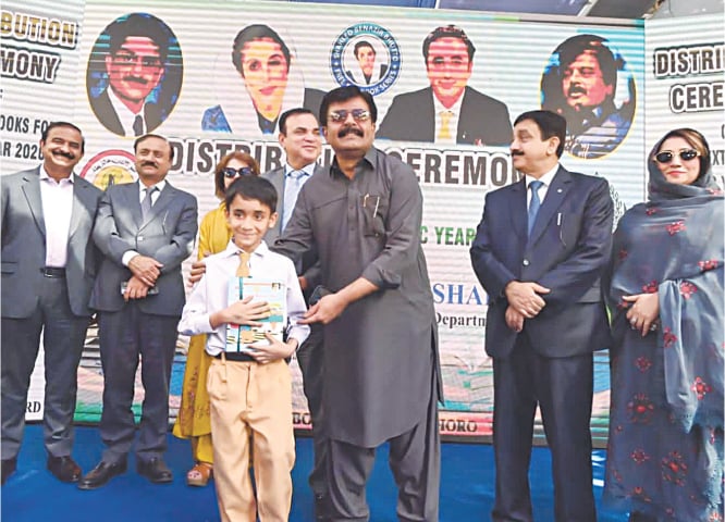 A student receives a set of free textbooks by Education Minister Sardar Shah at the ceremony on Thursday.&mdash;Dawn