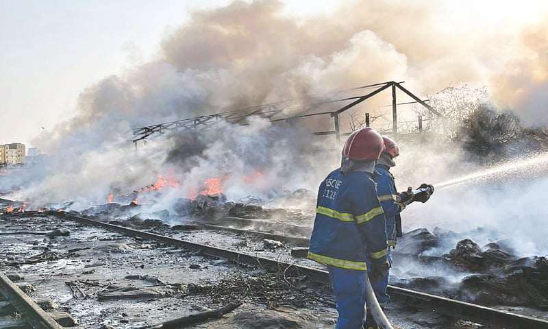 Firefighters hose down flames at the railway tracks near PIDC.—PPI Firefighters hose down flames at the railway tracks near PIDC.—PPI