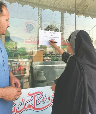 An official of the local administration seals a shop for violating official price list in Taxila on Saturday. &mdash; Dawn