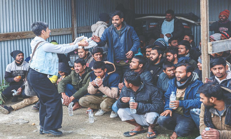 A WOMAN offers food and water to migrants at a port in Greece.&mdash;AFP