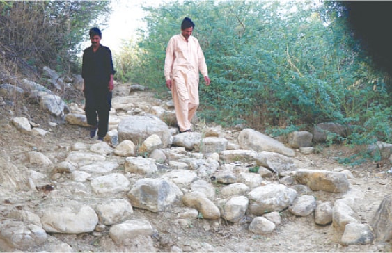Abdul Qayum and another villager walk along the stone-built pathway of the village. Stones gathered from the hills around serve as the pavement material for the streets. &mdash; Photos by the writer