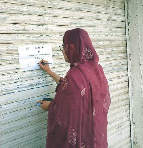 A price magistrate seals a shop for violation of official price list in Taxila on Saturday. — Dawn