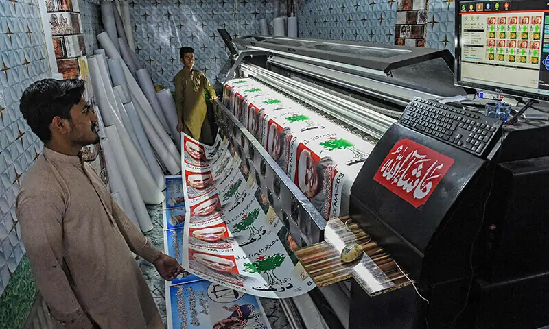 Workers print election posters on a printing press. &mdash; AFP/File