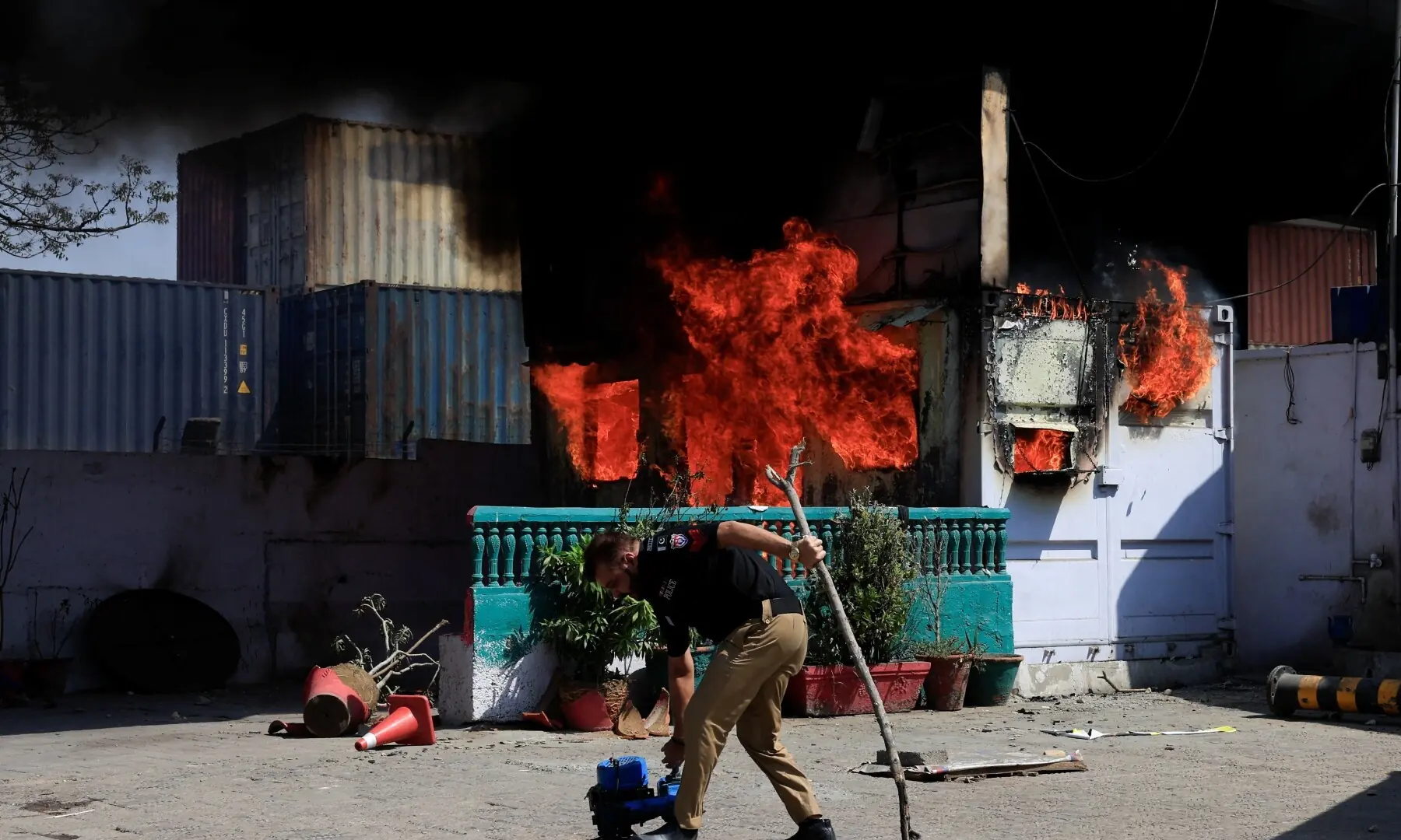 A police officer retrives items in front of a police checkpost burned by protesters near the US Consulate General in Karachi on March 1, 2026. &mdash; Reuters