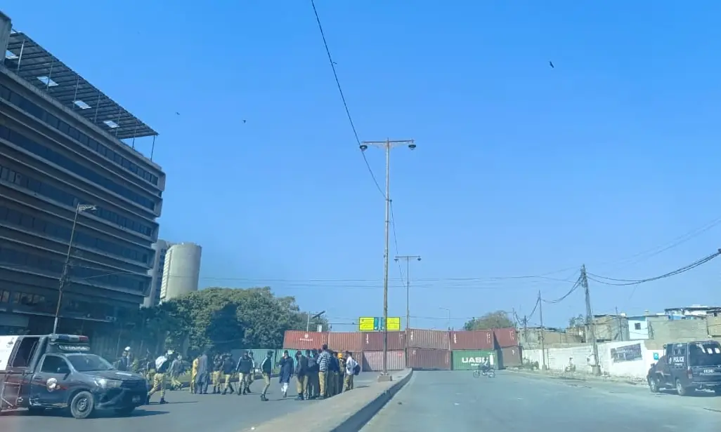 Containers are placed on the MT Khan Road to block it, with police personnel standing guard nearby, in Karachi on March 2, 2026. &mdash; Muskaan Mujahid