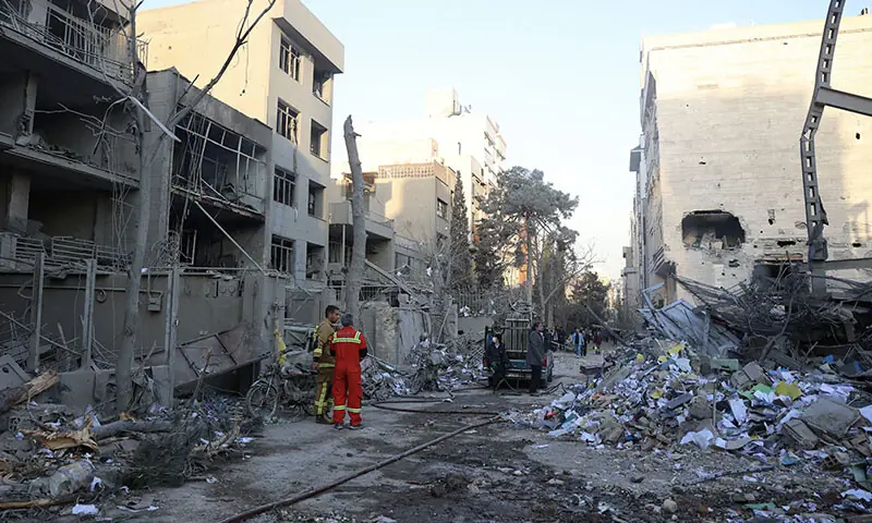 Firefighters stand next to the rubble of residential buildings near Niloufar Square in Tehran, Iran on March 2. &mdash; AFP
