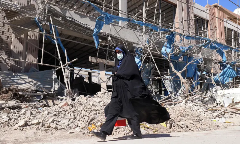 A woman walks past a heavily-damaged building near Ferdowsi square in Tehran on March 3, 2026. — AFP