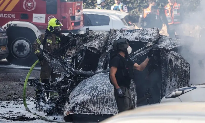 Israeli emergency personnel work to extinguish the burning wreckage of a car at a site struck by a projectile in Ramat Gan near Tel Aviv on March 3. &mdash; AFP