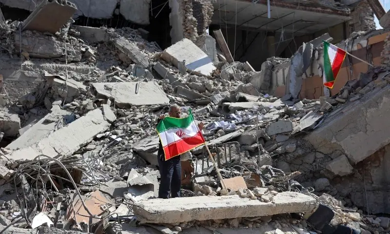 A man holds an Iranian flag amid the debris of a destroyed building following airstrikes in central Tehran, Iran on March 4. &mdash; AFP
