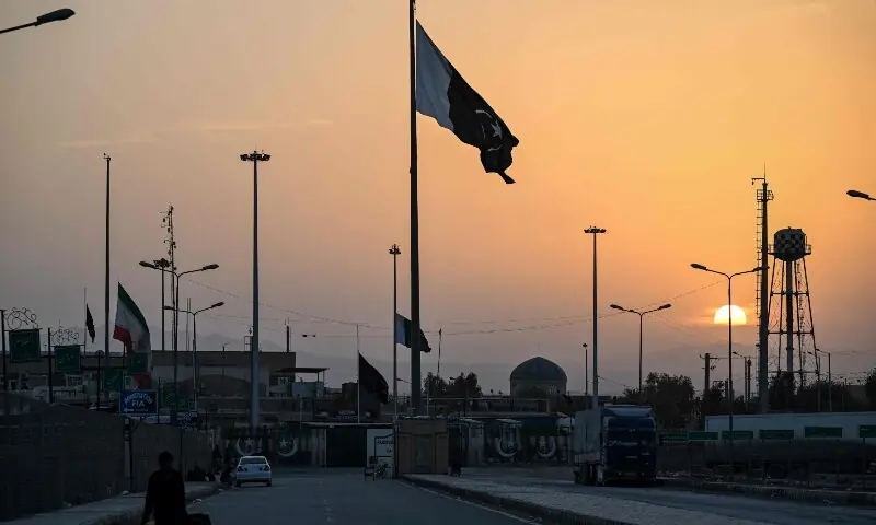 An Iranian national flag (L) flies at half-mast as Pakistan&rsquo;s flag (C) flutters during sunset at the Pakistan-Iran border crossing at Taftan, Balochistan on March 4. &mdash; AFP