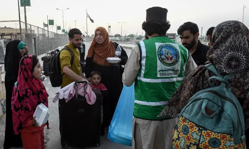 A volunteer distributes iftar meals to Pakistani nationals while crossing the Taftan border after returning from Iran, in Balochistan on March 4, amid ongoing US-Israeli strikes on Iran. &mdash; AFP