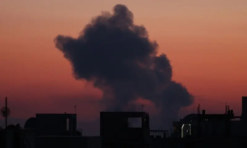 The sun sets as a black plume of smoke ascends from the site of an airstrike in a central area of Tehran, Iran on March 6. &mdash; AFP