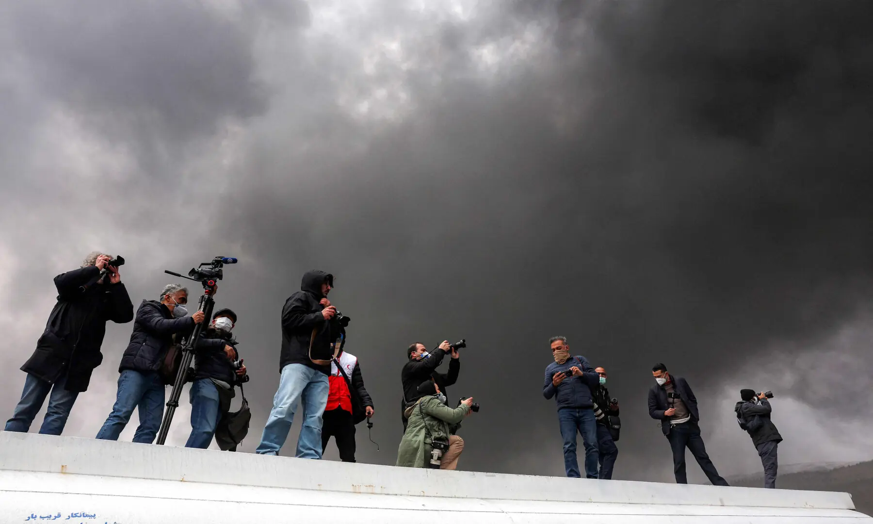 Journalists stand atop a fuel tanker as they cover a nearby ongoing fire following an overnight airstrike on the Shahran oil refinery in northwestern Tehran on March 8, 2026. &mdash; AFP
