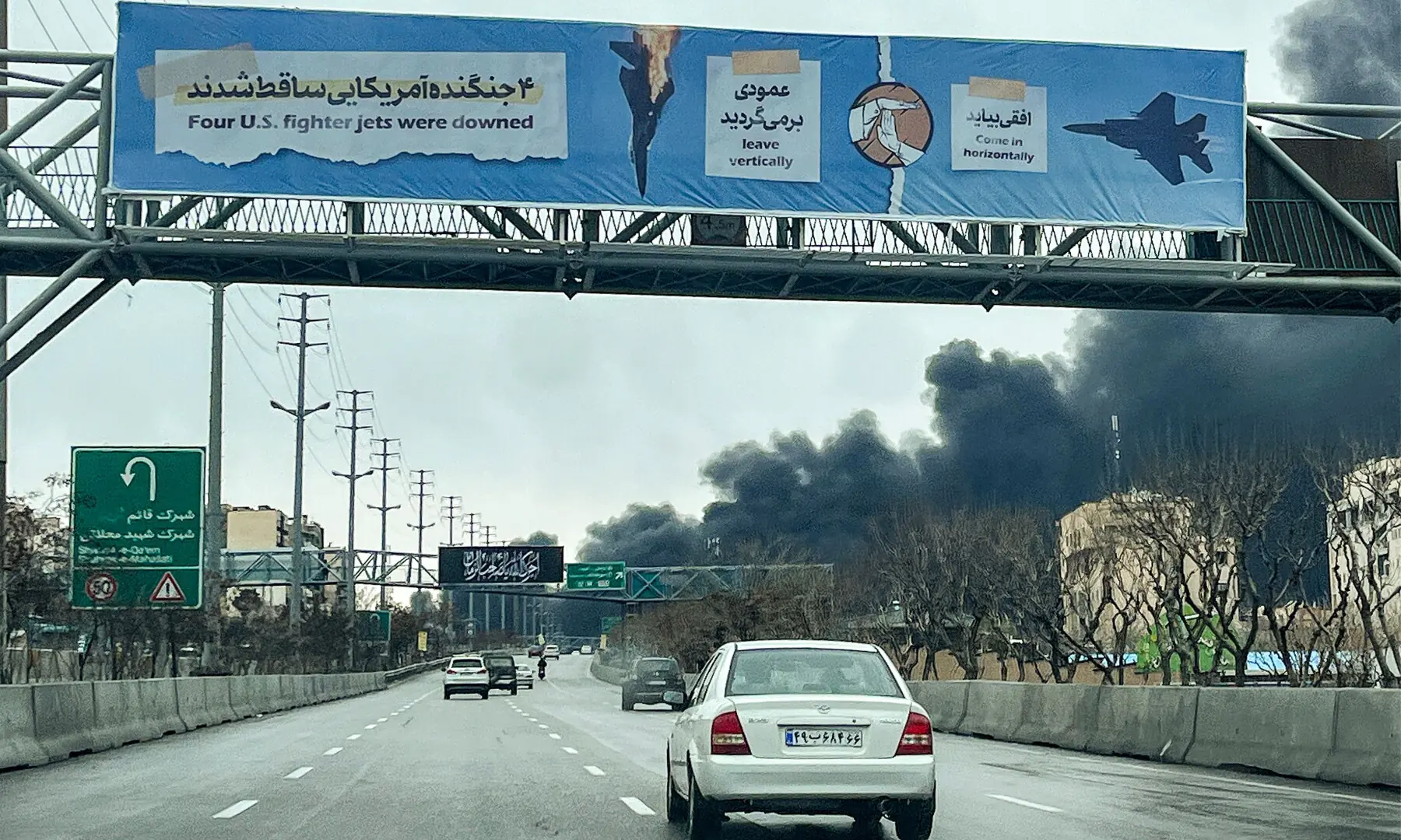 Vehicles move along a highway near plumes of black smoke billowing, in Tehran on March 8, 2026. &mdash; AFP