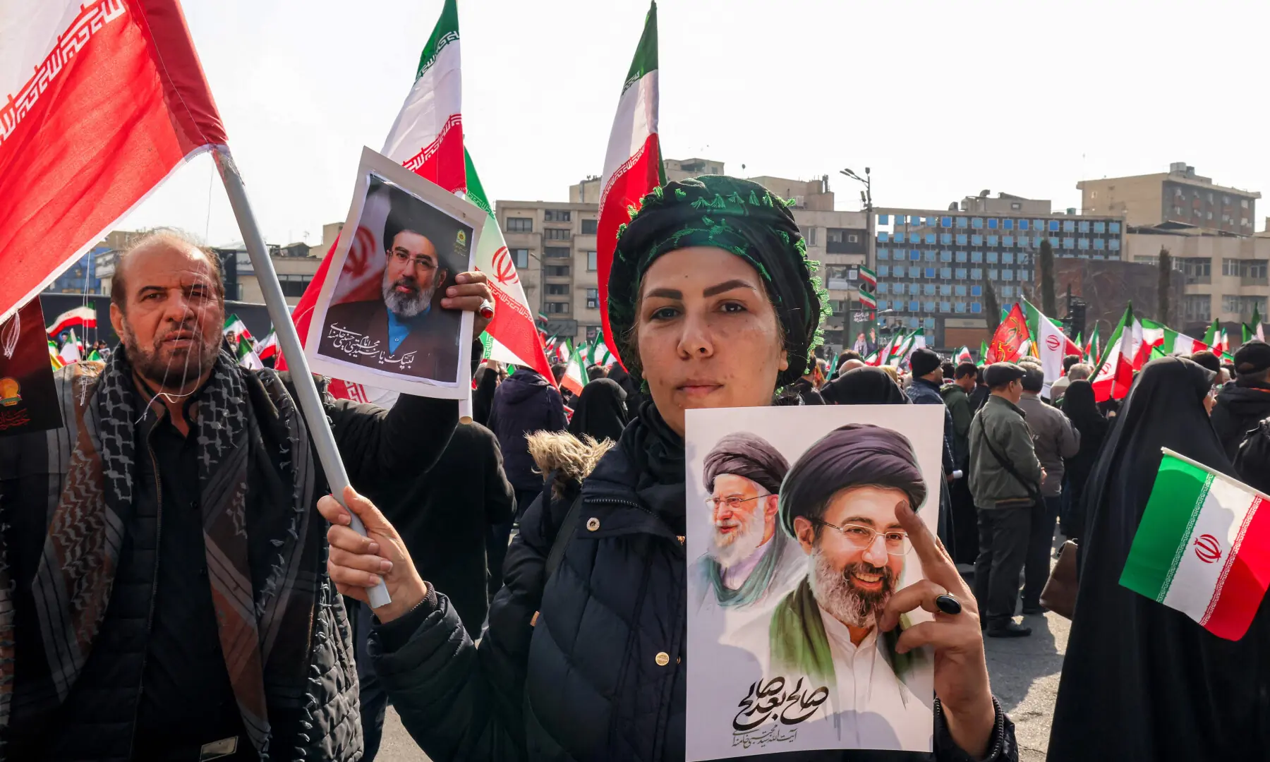 A woman poses with a picture of Iran&rsquo;s new Supreme Leader Ayatollah Mojtaba Khamenei (R), next to his late father Ali Khamenei, during a rally in support of him at Enghelab Square in central Tehran on March 9, 2026. &mdash; AFP