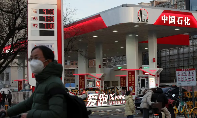 A cyclist waits to cross a road near a Sinopec gas station in Beijing, China on March 9, 2026. — Reuters