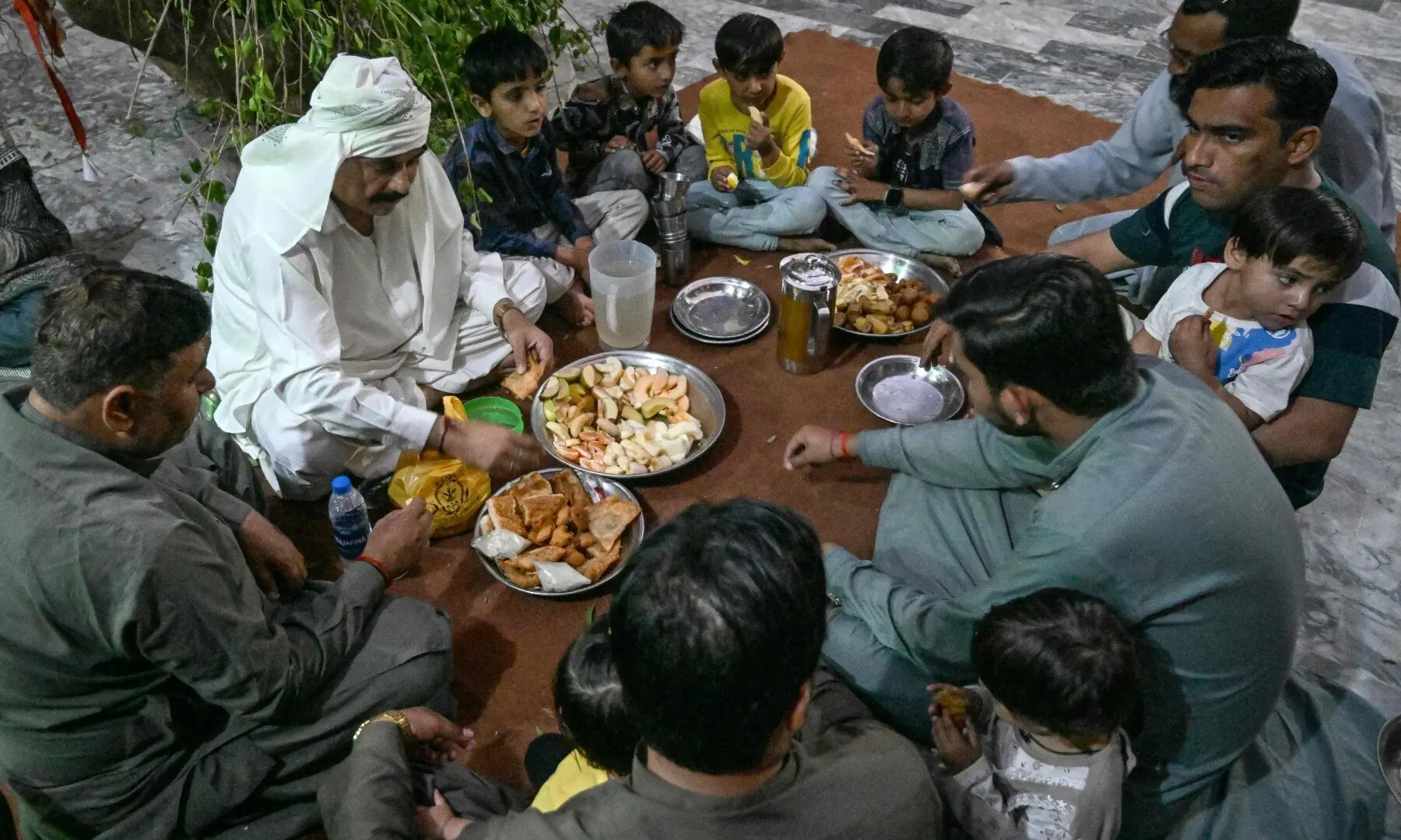 This photograph taken on February 26, 2026 shows Mohan Lal Malhi (2L), a Hindu caretaker of a Sufi shrine, breaking his fast during Ramazan at Mithi in the Tharparkar district of Sindh. &mdash; AFP