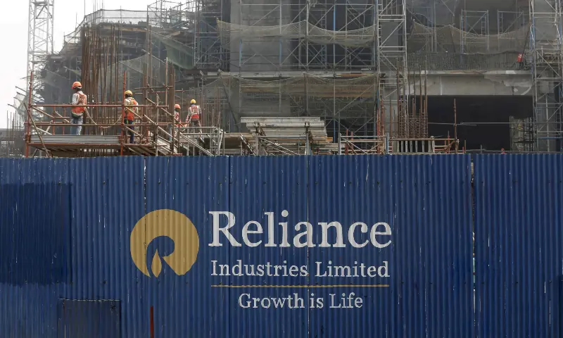 Labourers work behind an advertisement of Reliance Industries Limited at a construction site in Mumbai, India on March 2, 2016. &mdash; Reuters/File