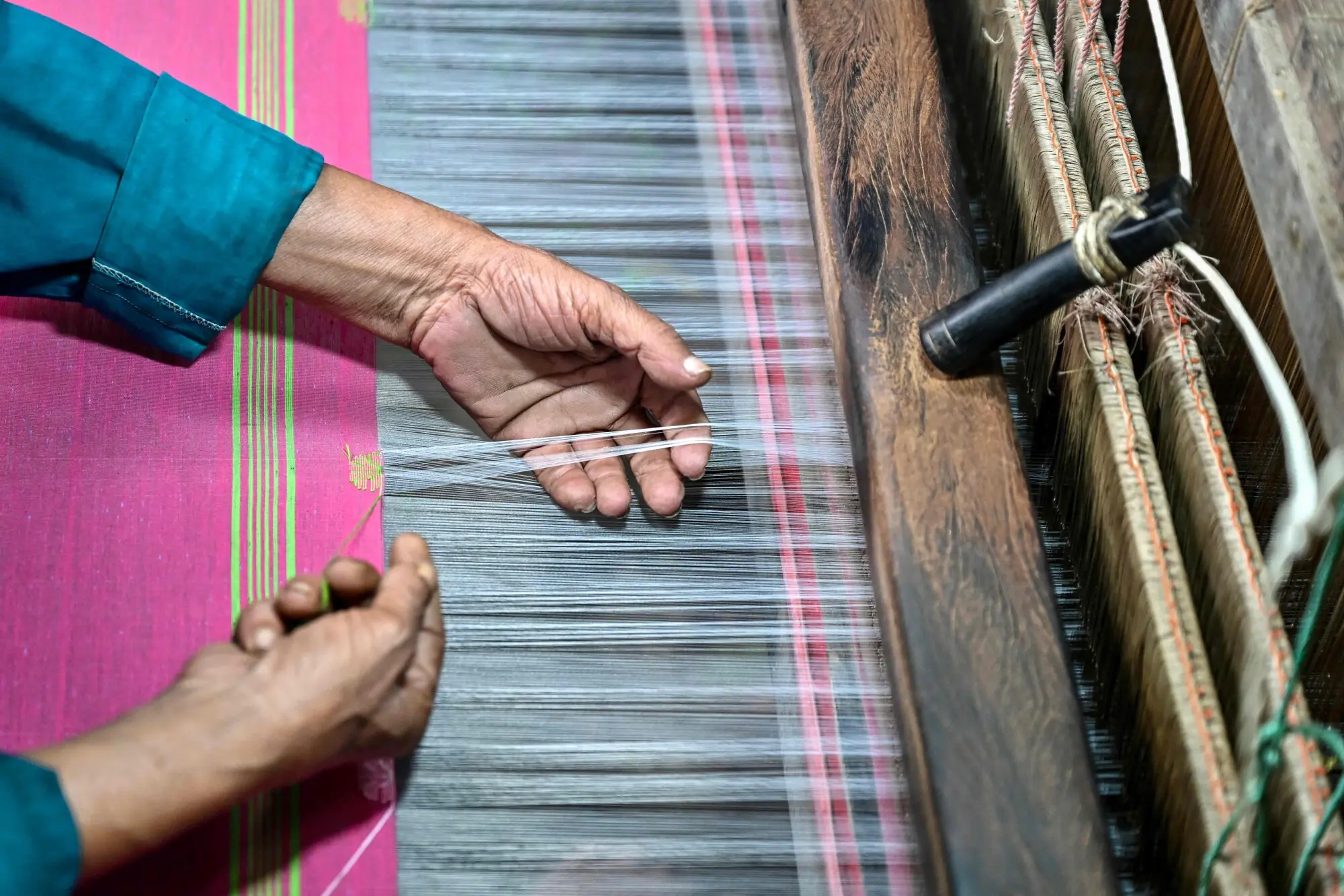 A craftsman weaves threads on a traditional handloom to make a Tangail sari. Photo: AFP