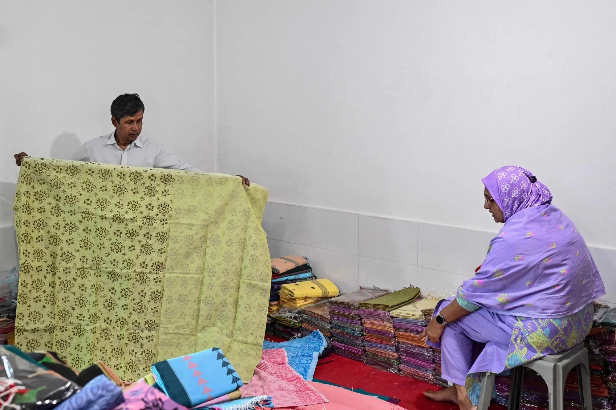A shopkeeper in Tangail, Bangladesh shows a sari to a customer. Photo: AFP