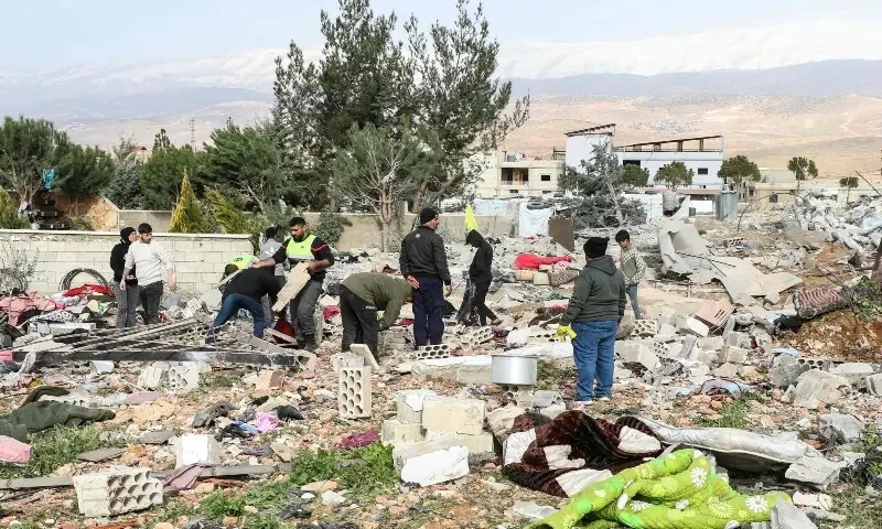 Residents and emergency personnel stand amid debris at the site of an overnight Israeli airstrike in the village of Younine, in Lebanon&rsquo;s Bekaa Valley, on March 12, 2026. &mdash;AFP