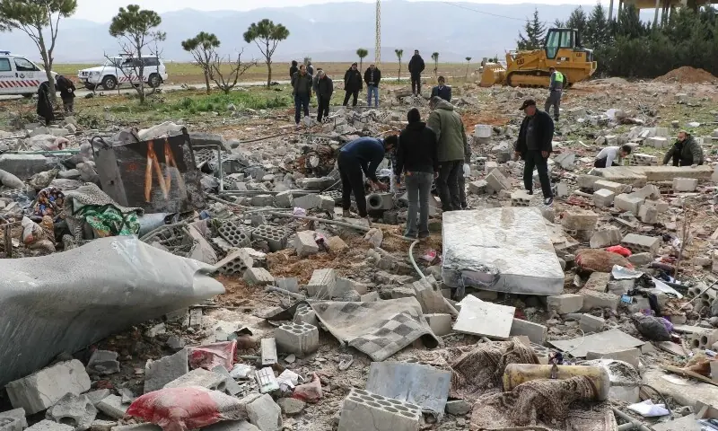 Residents and emergency personnel stand amid debris at the site of an overnight Israeli airstrike in the village of Younine, in Lebanon&rsquo;s Bekaa Valley, on March 12, 2026. &mdash;AFP