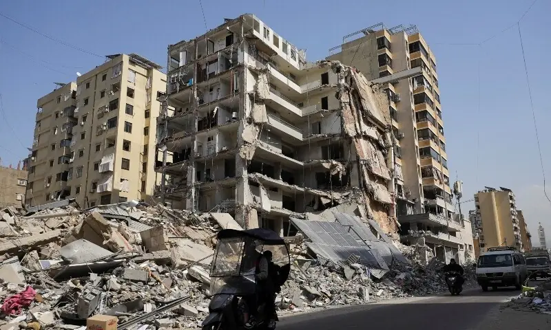 People ride a scooter next to a damaged building in the aftermath of Israeli strikes, amid an escalation between Hezbollah and Israel, amid the US-Israeli conflict with Iran, in Beirut&rsquo;s southern suburbs, Lebanon, March 12. &mdash; Reuters