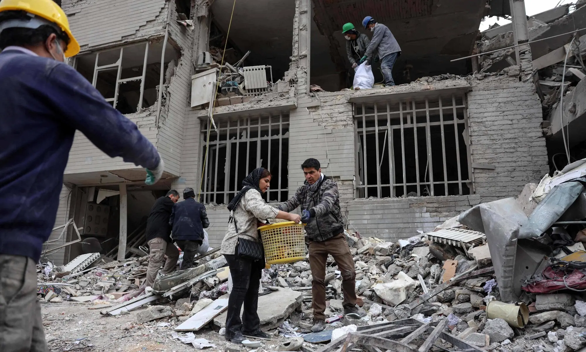 TOPSHOT - Iranians collect belongings from the rubble of a damaged residential building in Tehran on March 12, 2026. The United States and Israel started striking Iran on February 28, killing the Iranian supreme leader and top military leaders, and prompting authorities to retaliate with strikes on Israel and across the Gulf. (Photo by AFP) /