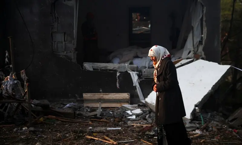 A woman walks at the site of an impact by an Iranian missile, amid the US-Israel conflict with Iran, in northern Israel, March 13, 2026. &mdash;Reuters