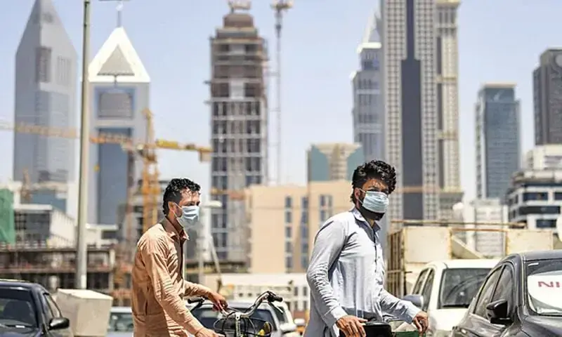 Migrant workers walk pushing bicycles along a street in Dubai&rsquo;s Satwa district in this file photo. &mdash; AFP