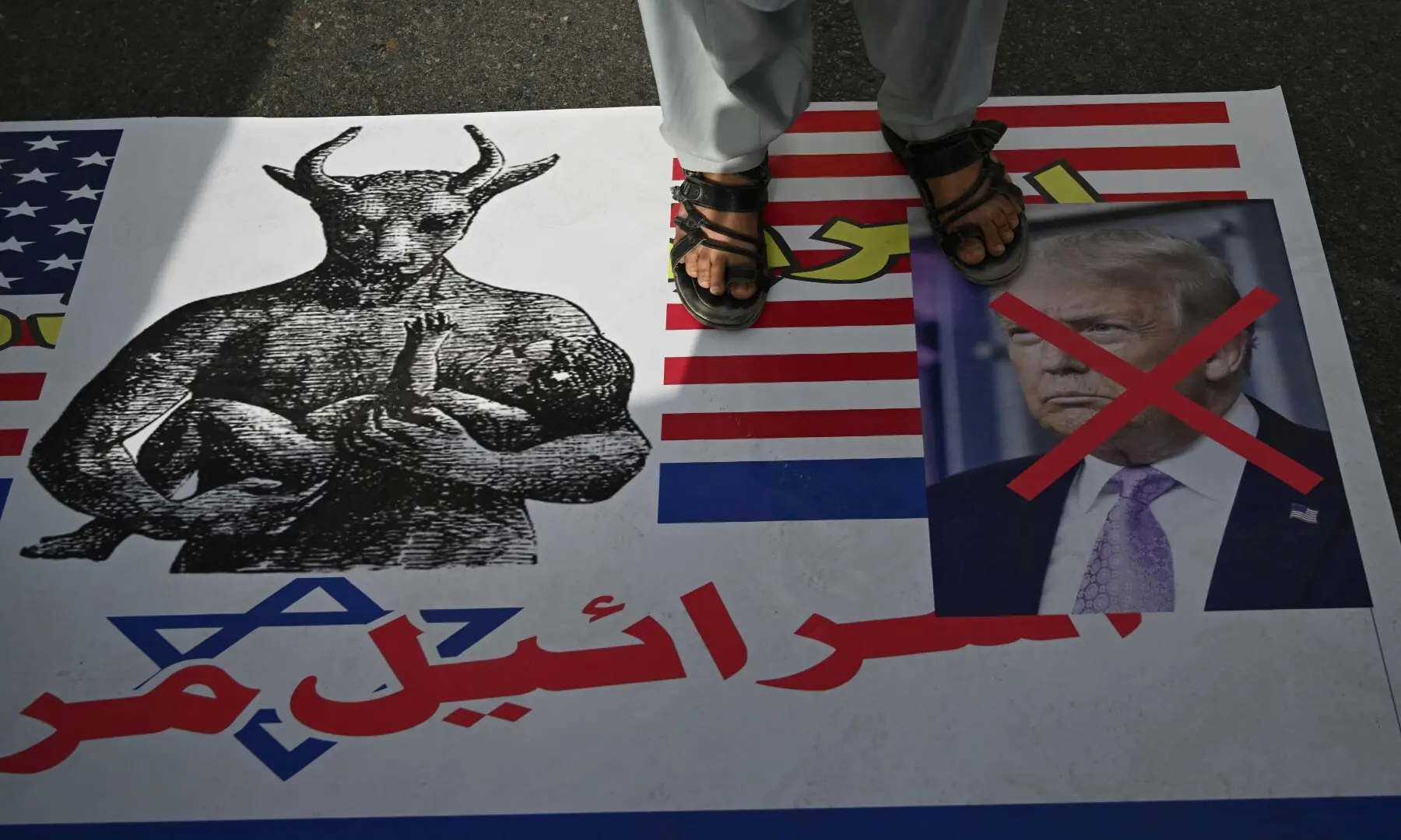 A demonstrator stands on a portrait of US President Donald Trump (R) during a rally to mark Al-Quds Day in Karachi on March 13. &mdash; AFP