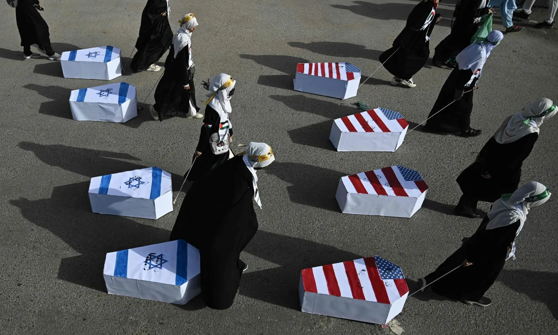 Women drag coffins wrapped with US and Israeli flags during a rally to mark Al-Quds Day in Karachi on March 13. &mdash; AFP