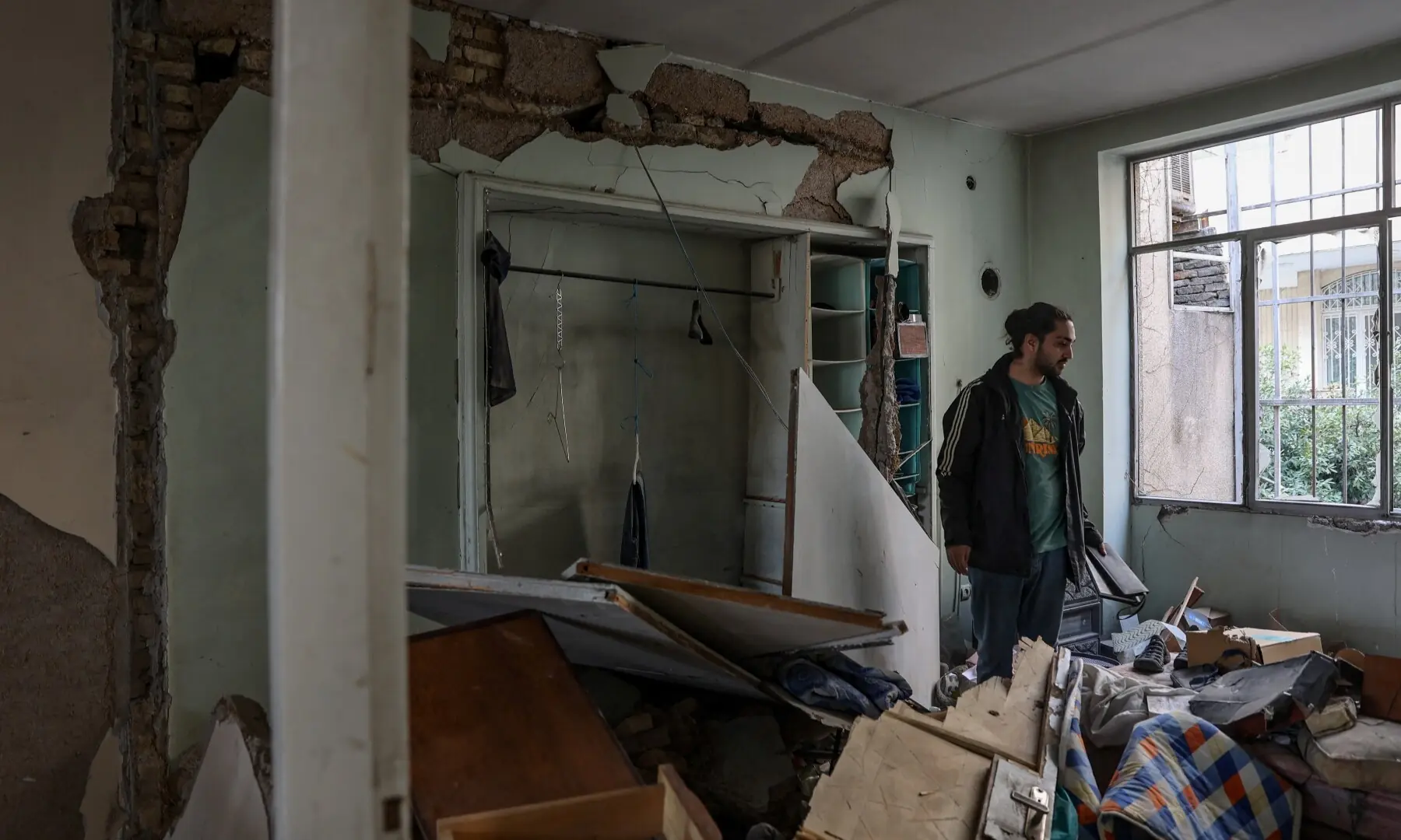 An Iranian man stands inside his house which was damaged by a strike, amid the US-Israeli conflict with Iran, in Tehran, Iran on March 14. &mdash; Reuters
