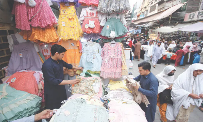A man buys children dresses at an outlet in Peshawar. &mdash; White Star