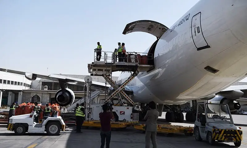 Afghan airport workers load the first cargo plane bound for India. ─ AFP