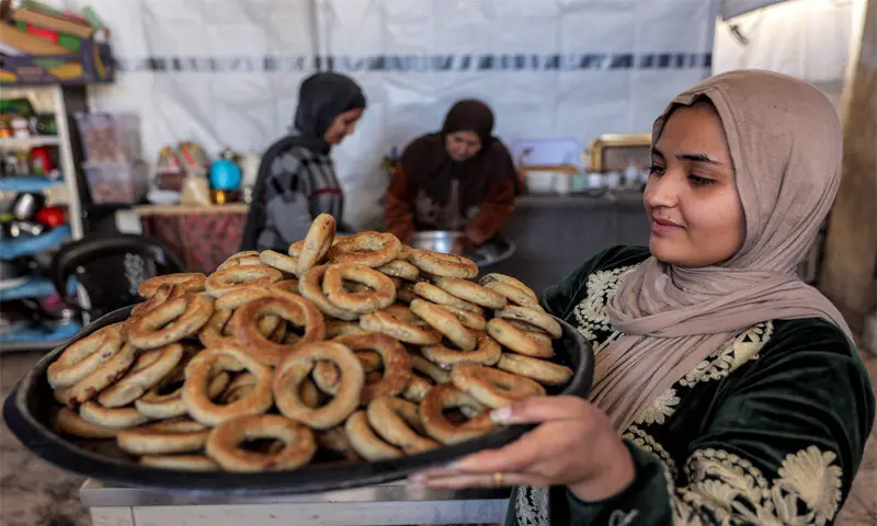 A woman holds a tray of freshly-baked ring-shaped ‘kaak’ biscuits ahead of Eidul Fitr in Gaza City.—AFP A woman holds a tray of freshly-baked ring-shaped ‘kaak’ biscuits ahead of Eidul Fitr in Gaza City.—AFP
