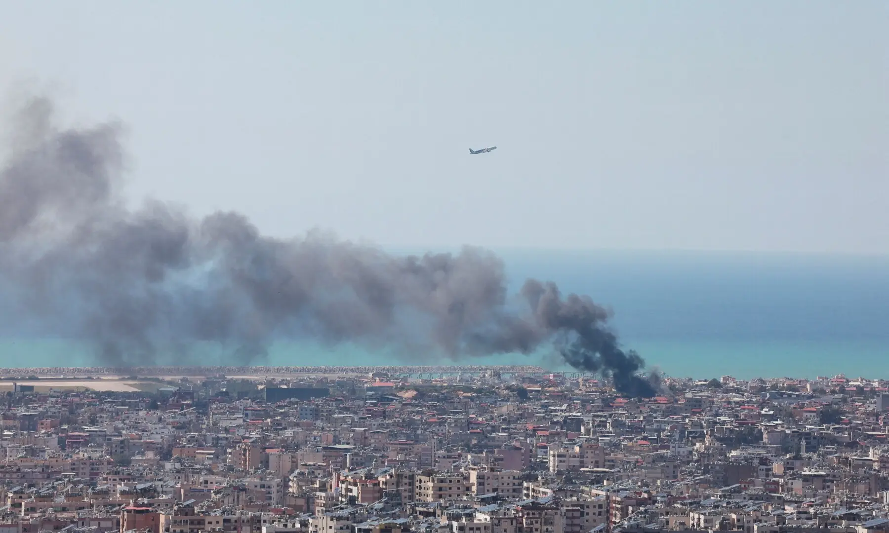 An aeroplane flies as smoke rises after an Israeli strike, following an escalation between Hezbollah and Israel, in Beirut, Lebanon on March 17. &mdash; Reuters