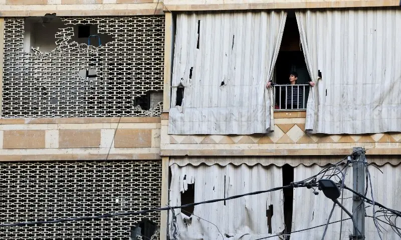 A person looks out of a balcony in the aftermath of an Israeli strike, following an escalation between Hezbollah and Israel amid the US-Israeli conflict with Iran, in Zuqaq al-Blat district in central Beirut, Lebanon, March 18, 2026. &mdash;Reuters