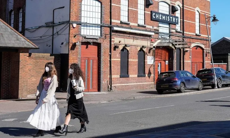 Pedestrians (L) wearing face masks walk past Club Chemistry (R), a nightclub linked to a recent outbreak of meningitis in Canterbury, south-east England on March 18, 2026. &mdash; AFP