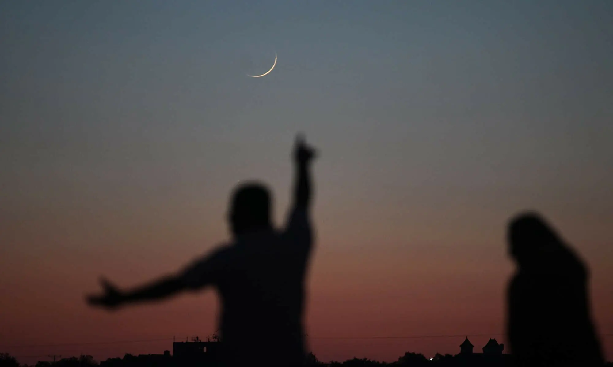 In this file photo, a Palestinian man points towards the moon in its Crescent form in Khan Yunis in the southern Gaza Strip. &mdash; AFP/File