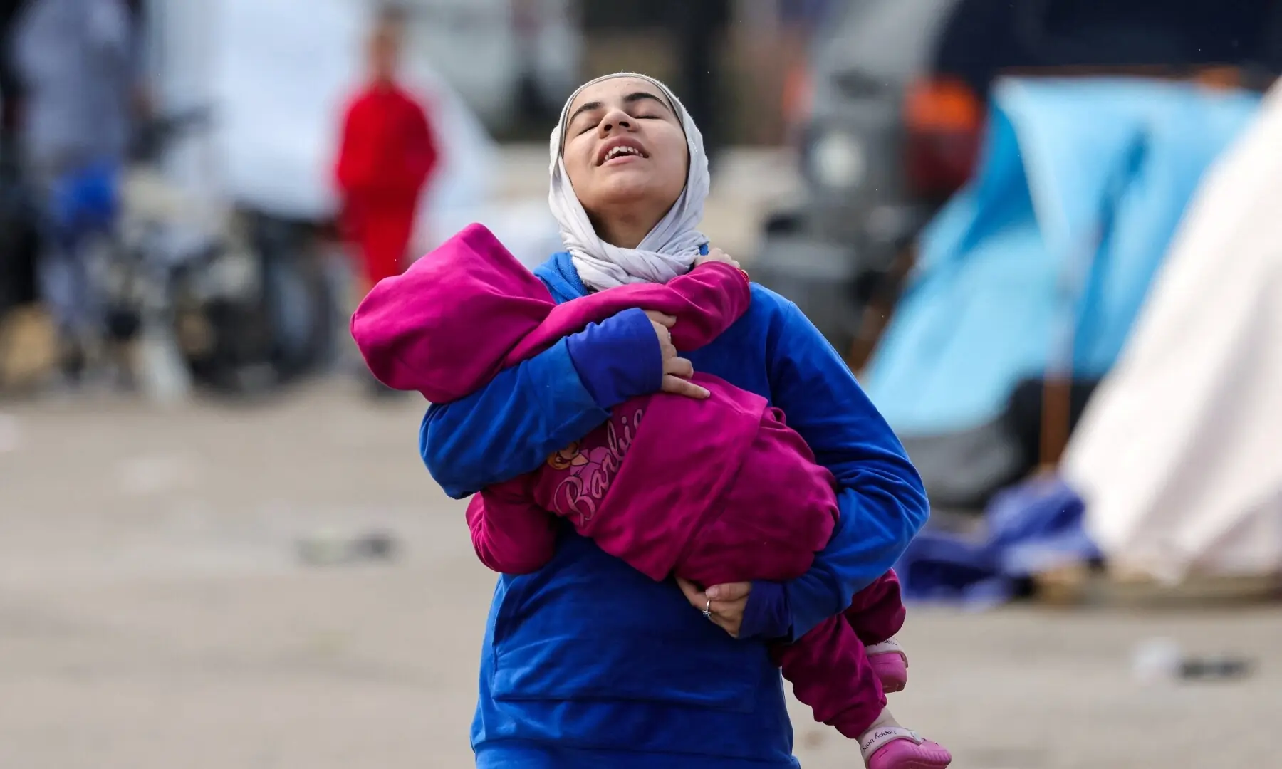 A woman carries a child near shelters of displaced people on the day Muslim worshippers attend Eidul Fitr prayers to mark the end of Ramazan in Beirut, Lebanon on March 20, 2026. &mdash; Reuters